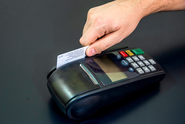 Female hand with credit card and bank terminal, Card machine or pos terminal with inserted blank white credit card isolated on black background