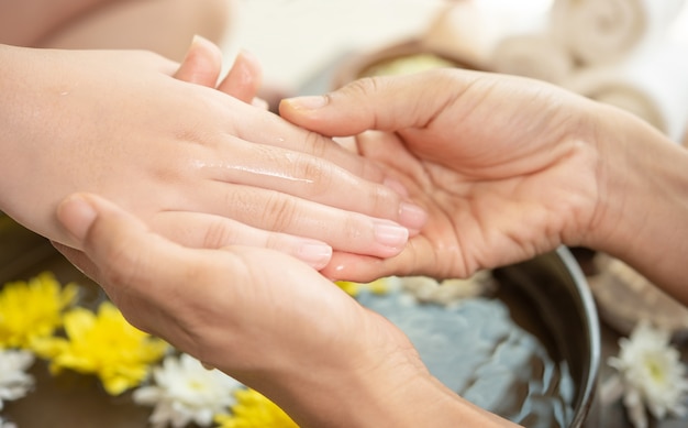 Free Photo female hands and bowl of spa water with flowers, close up. hands spa.