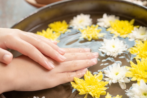 Free photo female hands and bowl of spa water with flowers, close up. hands spa.