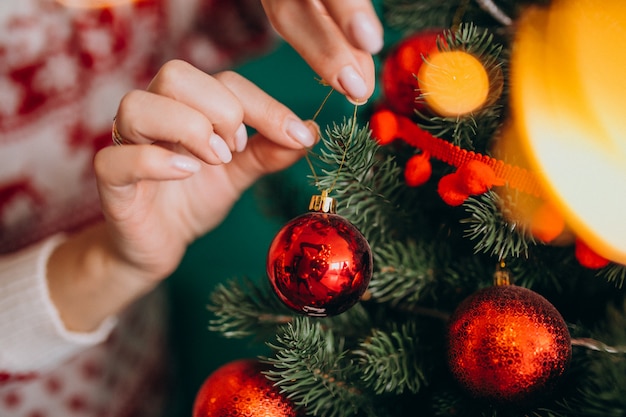 Female hands close up, decorating christmas tree with red balls