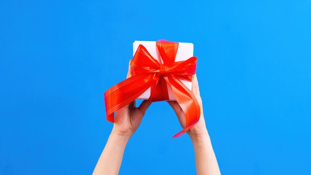 Female hands hold a gift box with red tape