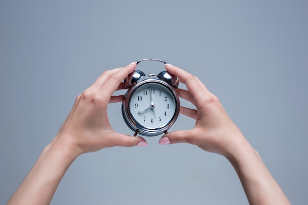 The female hands holding old style alarm clock