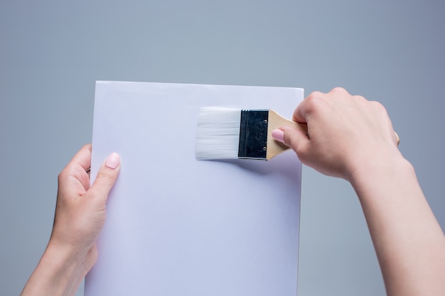 female hands holding painting brush on white canvas