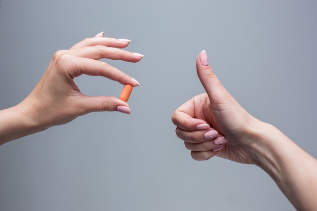 The female hands holding pill capsule closeup.