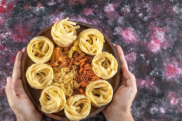 Free photo female hands holding plate of various macaroni.