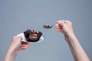 Free photo female hands keeping cake with spoon on gray