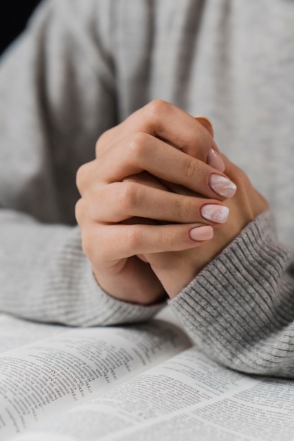 Female hands in praying position with bible