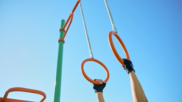 Female hands taking gymnastic rings at sports ground