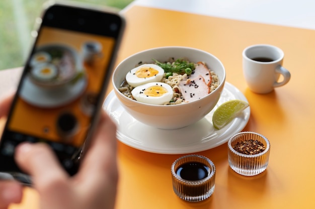 Free photo female hands taking photo of a bowl of ramen