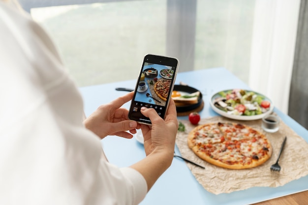 Female hands taking photo of sliced pizza