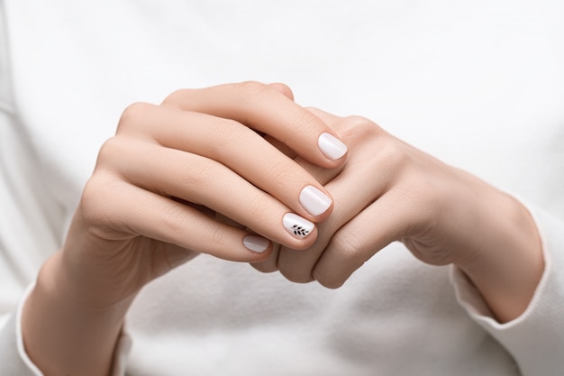 Female hands with white nail design, close up.