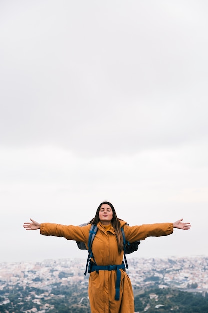 Free photo a female hiker outstretching her hands enjoying the fresh air on top of mountain