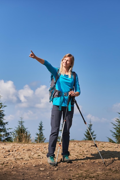 Female hiker standing on mountain road and pointing at something