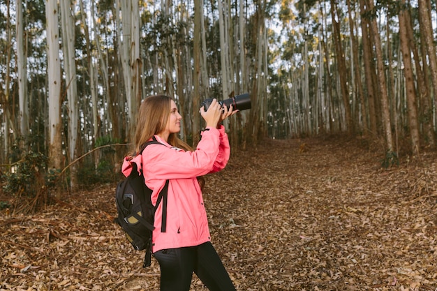 Free photo female hiker taking picture of forest trees