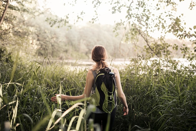 Free photo female hiker walking in the green grass