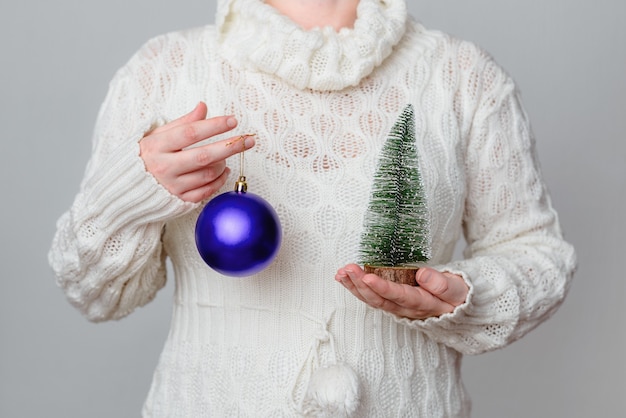 Free photo female holding a purple christmas ball and decorative small tree