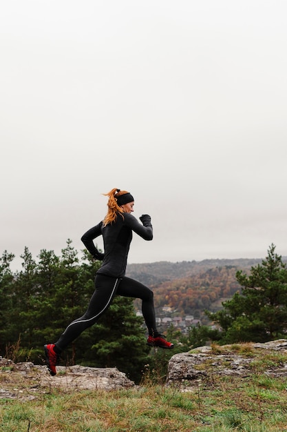 Free photo female jogger jumping over the rocks