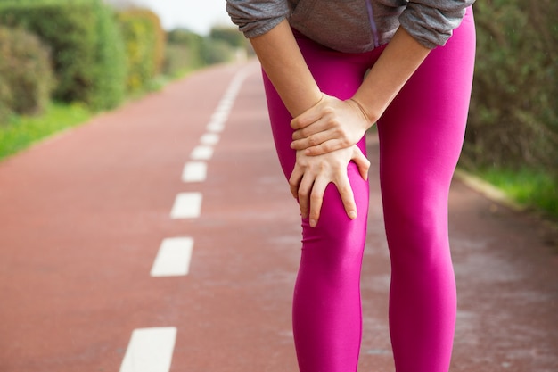 Free photo female jogger wearing pink tights, injuring knee