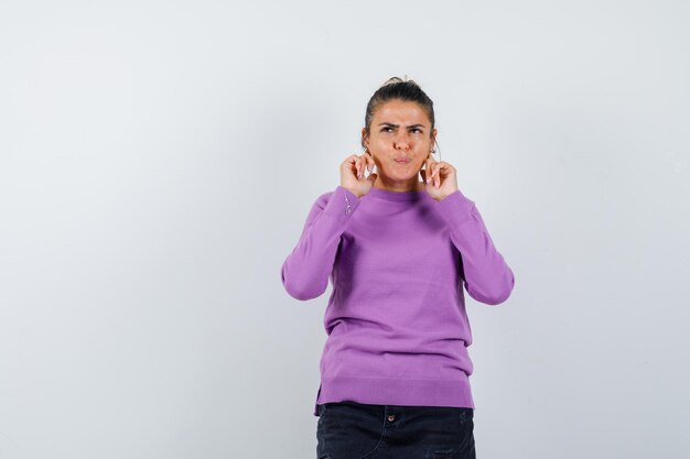 Female keeping fingers on head in wool blouse and looking pensive 