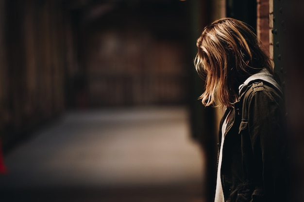 Female leaning against the wall looking down in a hallway with blurred background in Alcatraz Island