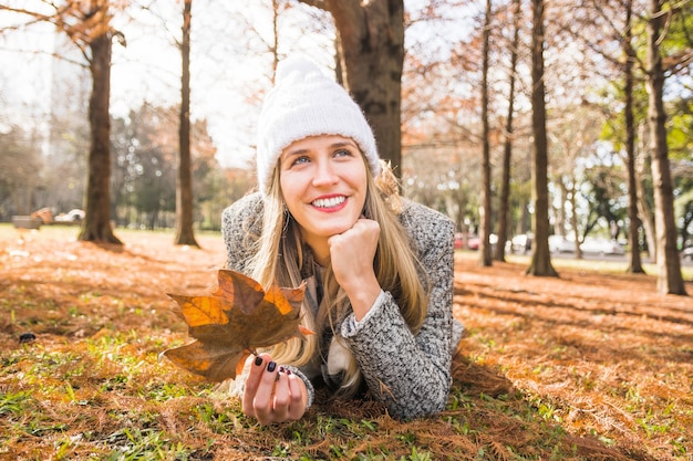 Free photo female lying in fall forest and smiling