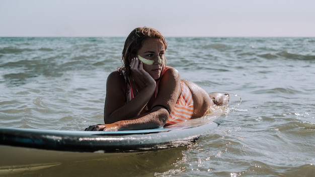 Free photo female lying on her surfboard