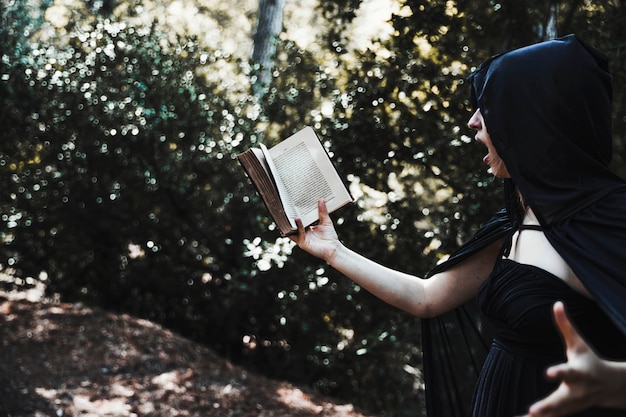 Free Photo female magician reading spell in thicket