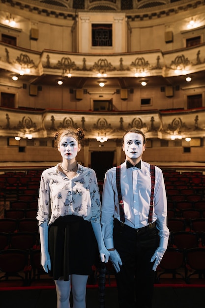 Free photo female and male mime artist standing on stage in the auditorium