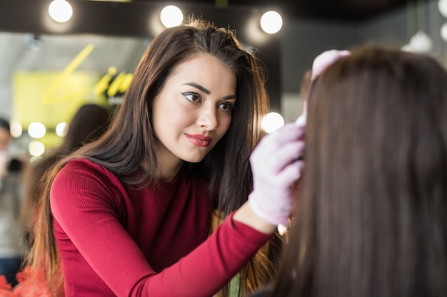 Free photo female master doing professional make up of young woman