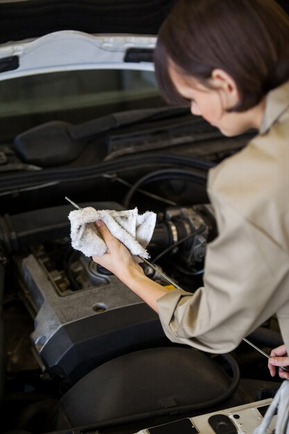 Female mechanic checking the oil level in a car engine