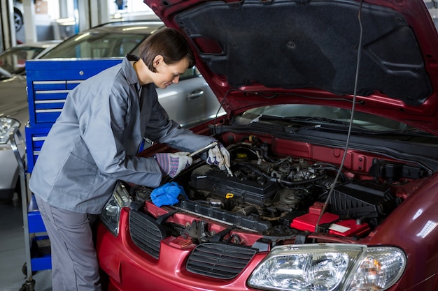 Free photo female mechanic checking the oil level in a car engine