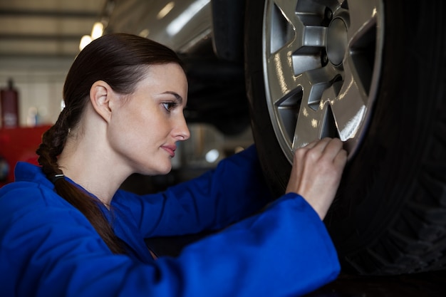 Female mechanic examining a car wheel