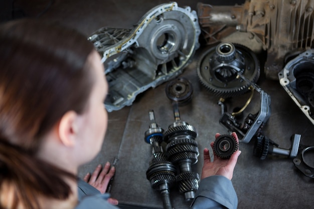 Free photo female mechanic holding spare parts of car