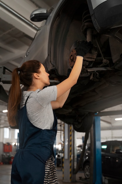 Free Photo female mechanic working in the shop on a car