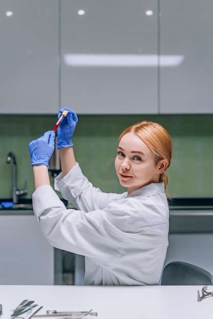 Free Photo female medical or scientific researcher looking at a test tube in a laboratory.