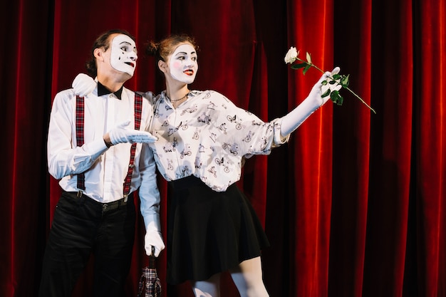 Free photo female mime holding white rose standing with male mime