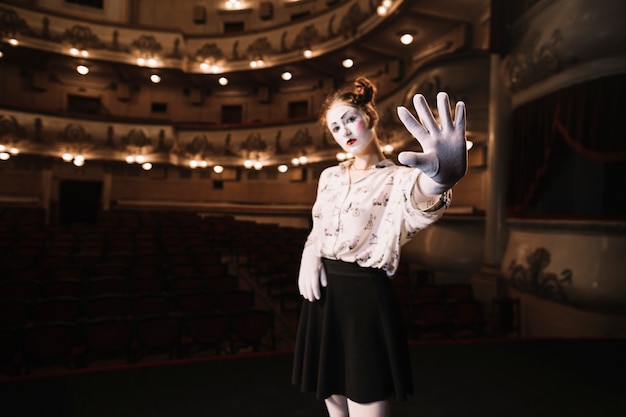 Free Photo female mime standing in auditorium showing stop gesture