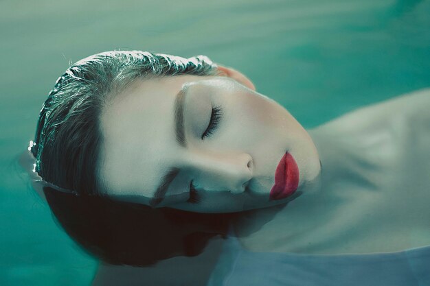 Female model in avantgarde makeup in water, sleepy position