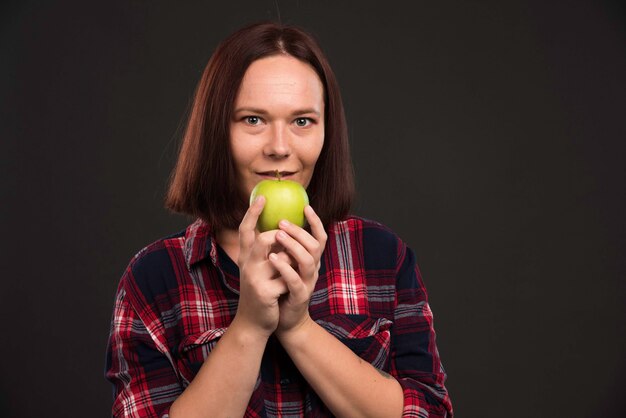 Female model in fall winter collection outfits holding a green apple and feeling excited.