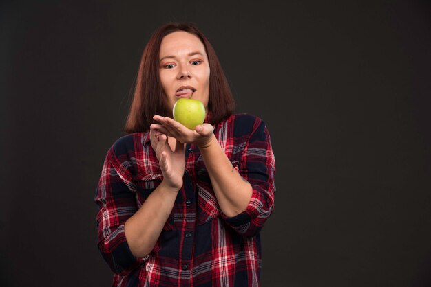 Female model in fall winter collection outfits holding a green apple and looks terrified. 