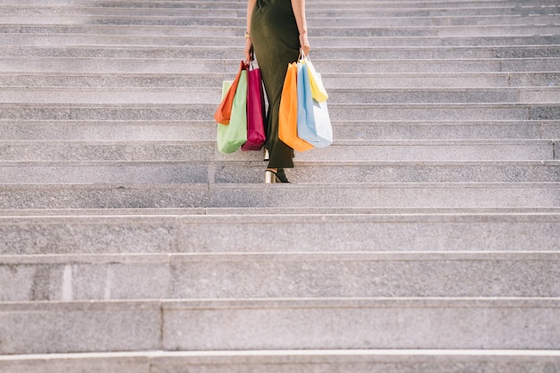 Free photo female model with shopping bags going upstairs