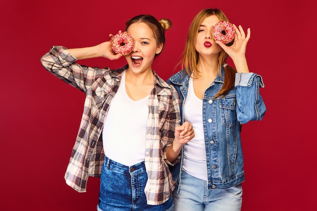 Free Photo female models holding pink donuts with sprinkles