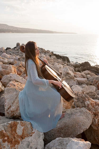 Free photo female musician playing cello outside at sunset