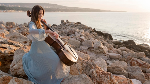 Female musician playing cello at sunset with copy space