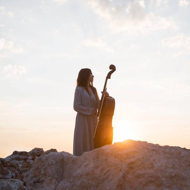 Female musician with cello outdoors at sunset