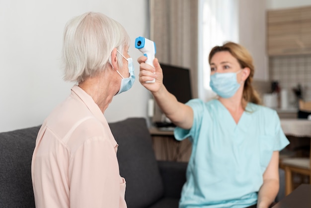 Female nurse checking elder woman's temperature