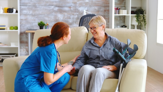 Female nurse talking with old woman with alzheimer in nursing home