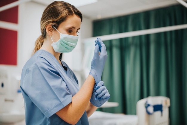 Free photo female nurse with a mask putting on gloves