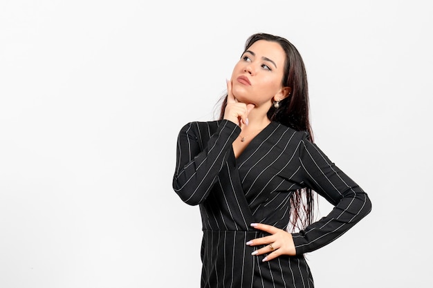 female office employee in strict black suit posing and thinking on white