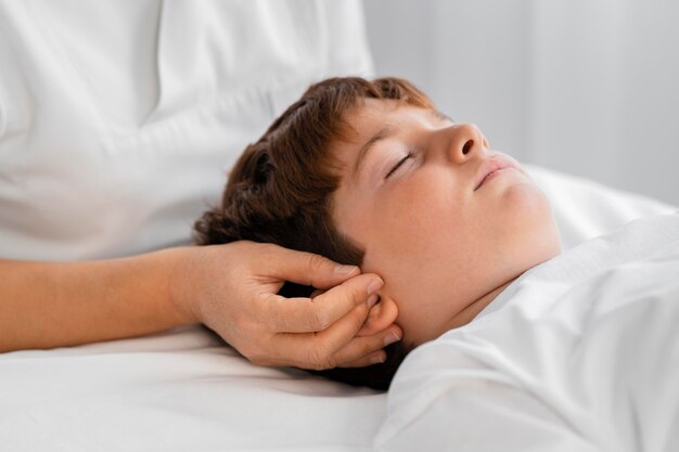 Female osteopathist treating a child by massaging his head